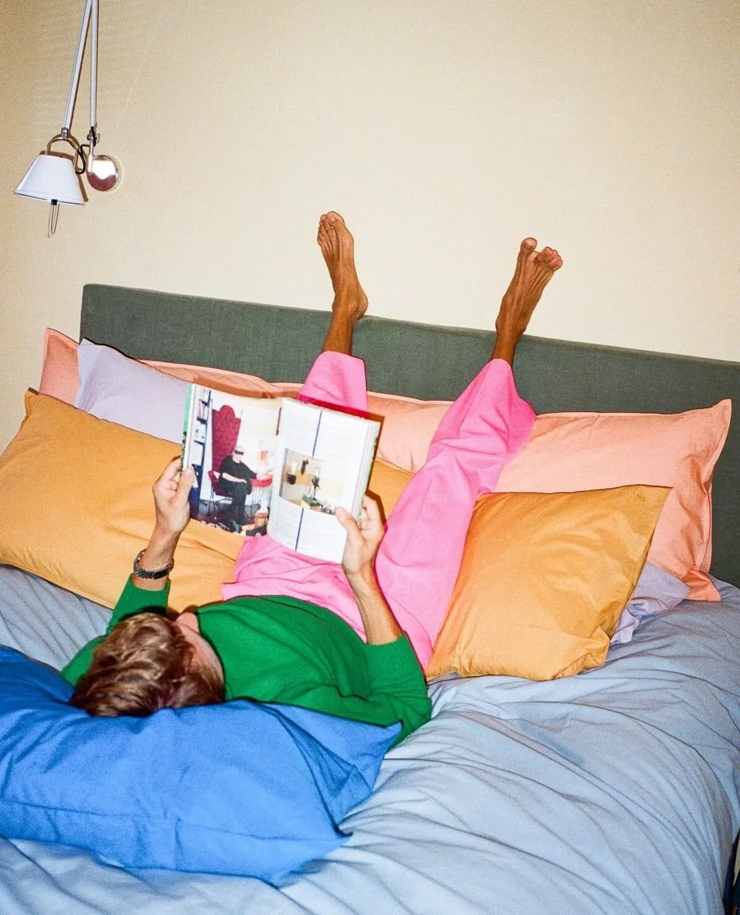 Person resting on colourful cushions reading a magazine